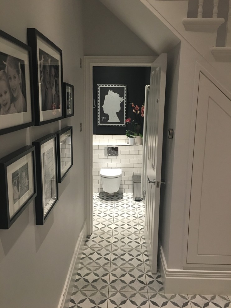 Small traditional powder room in London with a wall-mount toilet, ceramic tile, black walls, ceramic floors and a wall-mount sink.