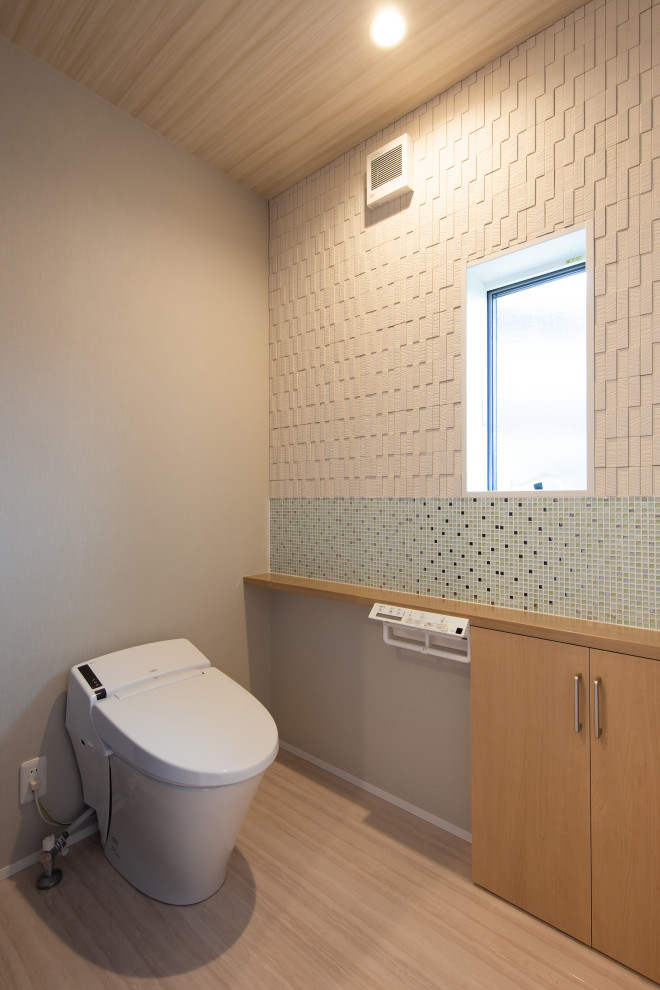 This is an example of a small modern powder room in Other with a one-piece toilet, green tile, glass tile, beige walls, vinyl floors, beige floor, beige benchtops, wallpaper and wallpaper.
