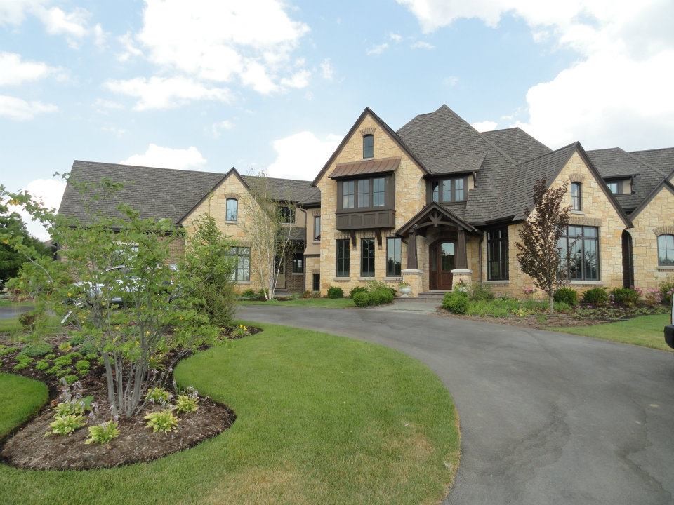 This is an example of a large traditional two-storey beige exterior in Chicago with stone veneer and a hip roof.
