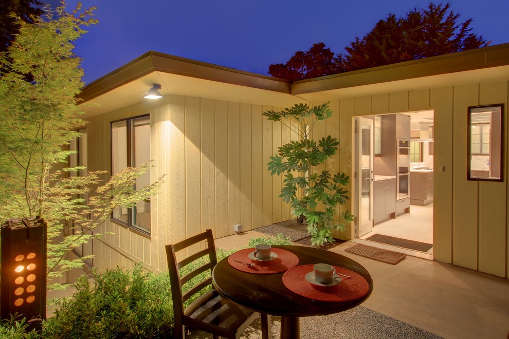 Photo of a midcentury side yard patio in Seattle with concrete slab.