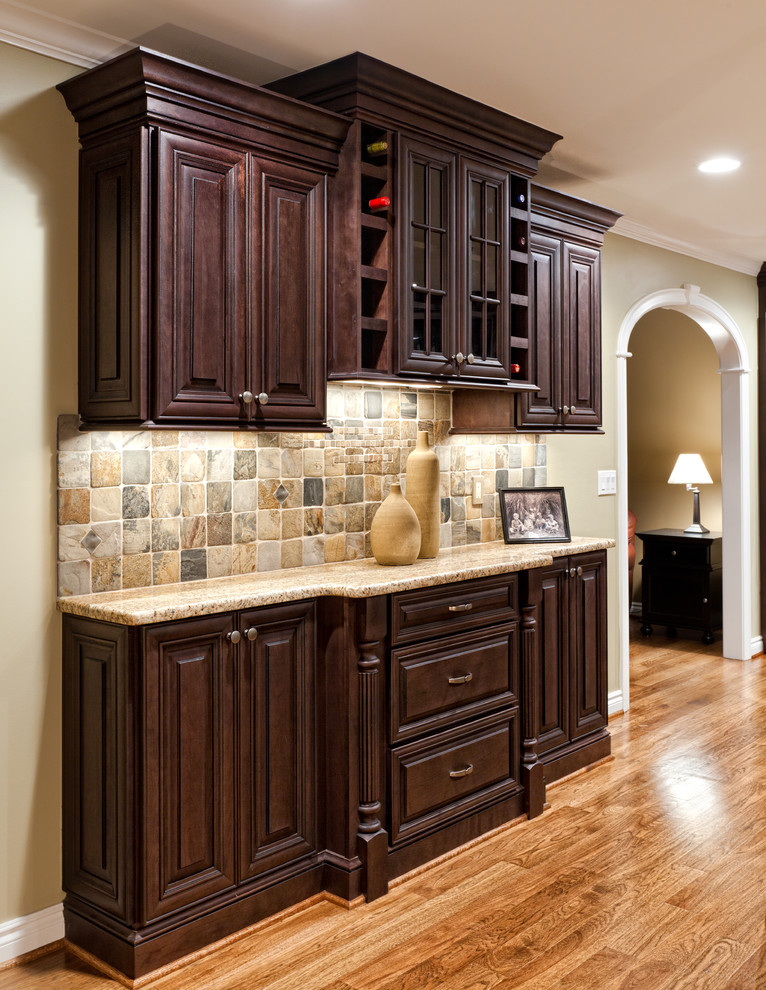 Inspiration for a large traditional u-shaped eat-in kitchen in Detroit with an undermount sink, raised-panel cabinets, dark wood cabinets, granite benchtops, multi-coloured splashback, stone tile splashback, stainless steel appliances, medium hardwood floors, with island and brown floor.