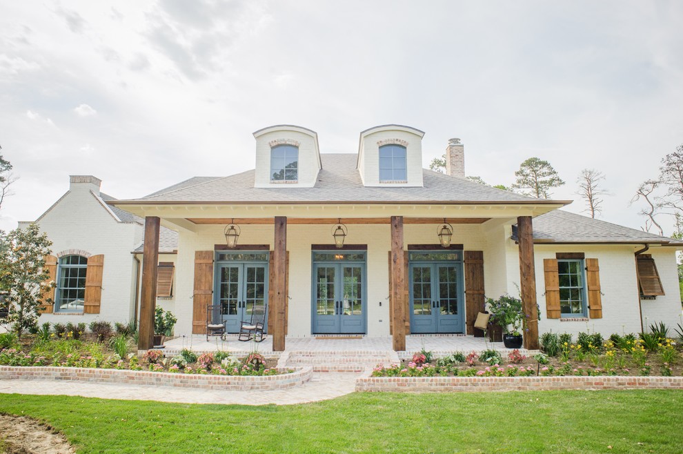 Photo of a large traditional two-storey brick white house exterior in Houston with a gable roof and a shingle roof.