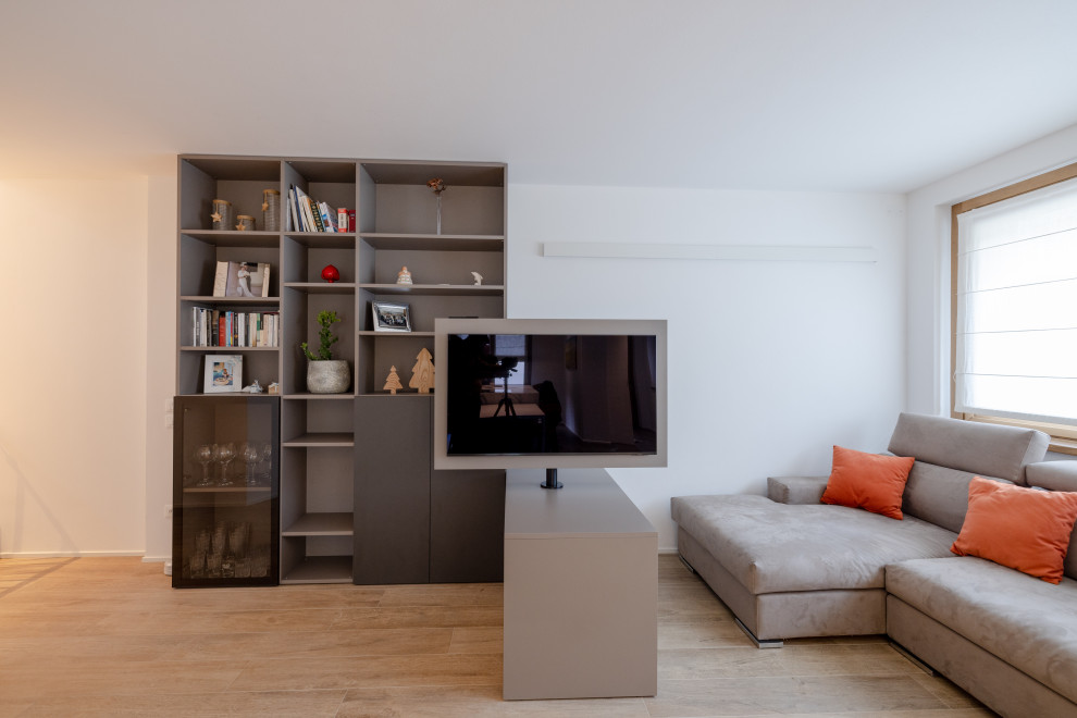 Стильный дизайн: большая открытая гостиная комната в современном стиле с с книжными шкафами и полками, белыми стенами, светлым паркетным полом, отдельно стоящим телевизором и бежевым полом - последний тренд