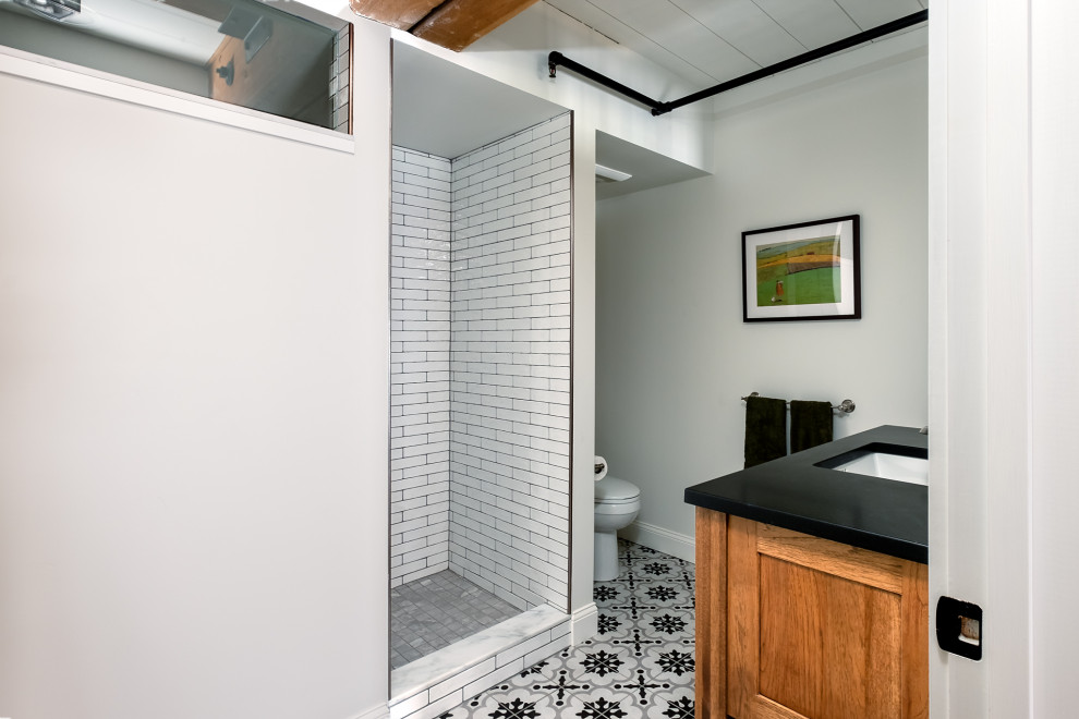 Mid-sized industrial master bathroom in Portland Maine with medium wood cabinets, an alcove shower, white tile, subway tile, white walls, mosaic tile floors, engineered quartz benchtops, multi-coloured floor, an open shower, black benchtops, a single vanity and a freestanding vanity.