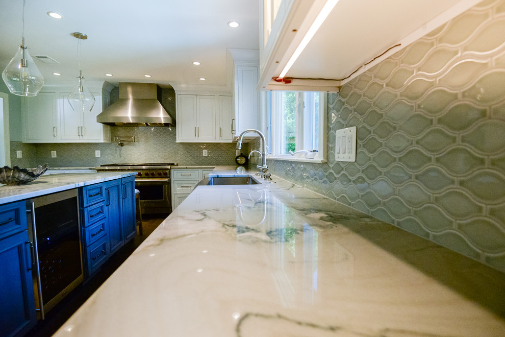 Example of a large transitional u-shaped medium tone wood floor and brown floor eat-in kitchen design in DC Metro with a farmhouse sink, recessed-panel cabinets, white cabinets, marble countertops, stainless steel appliances and an island