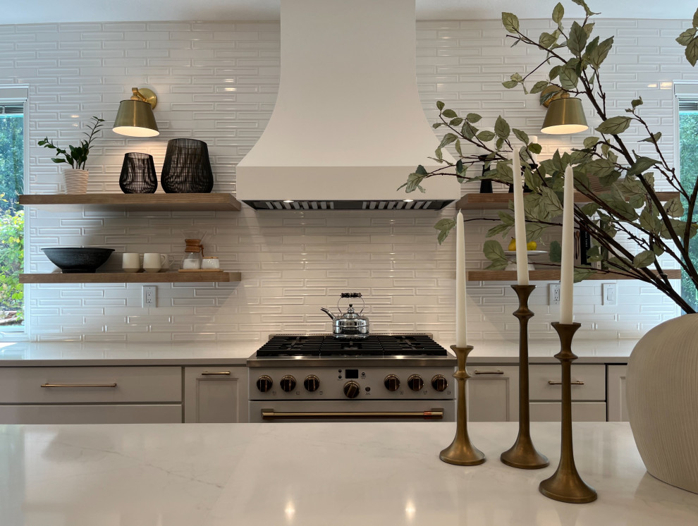 Large transitional l-shaped light wood floor and beige floor eat-in kitchen photo with a farmhouse sink, shaker cabinets, white cabinets, quartz countertops, white backsplash, ceramic backsplash, white appliances, an island and white countertops