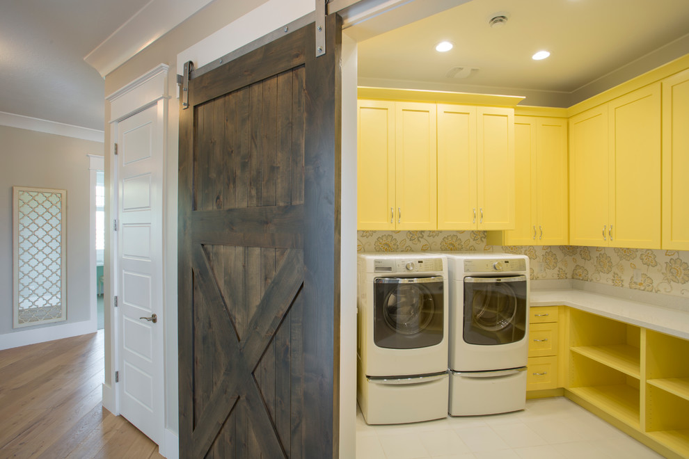Photo of a beach style u-shaped dedicated laundry room in Salt Lake City with a drop-in sink, shaker cabinets, yellow cabinets, quartzite benchtops, ceramic floors, a side-by-side washer and dryer and grey walls.