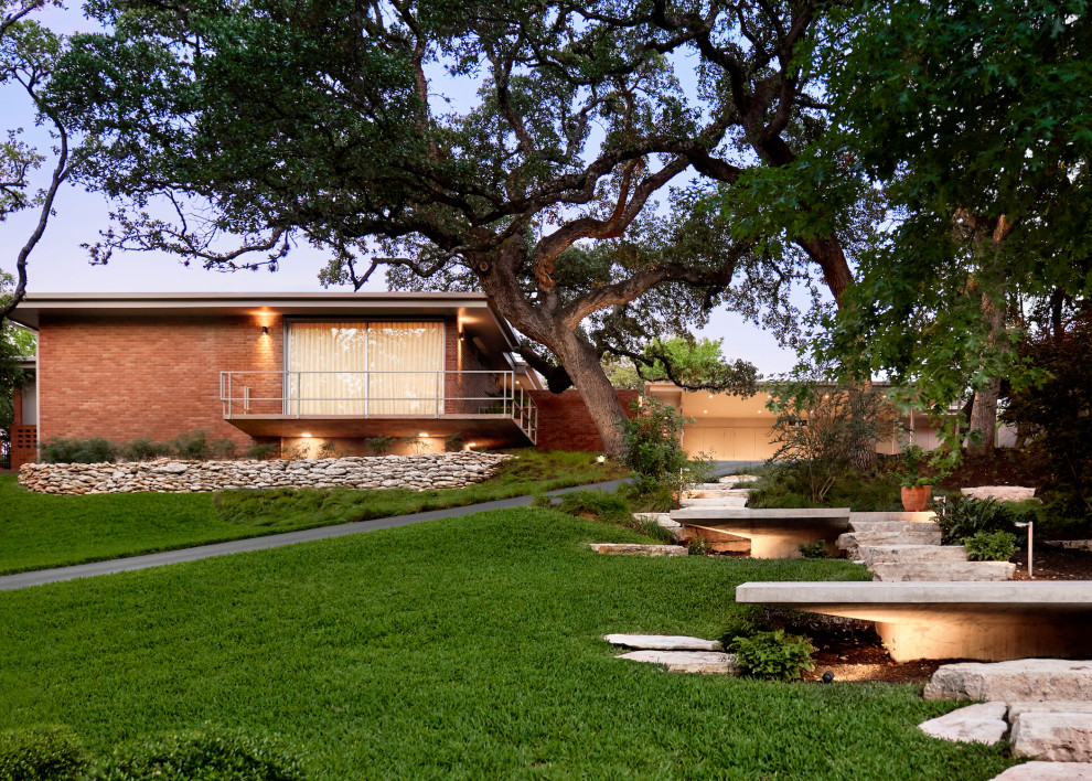 Inspiration for a mid-sized midcentury one-storey brick orange house exterior in Austin with a flat roof.