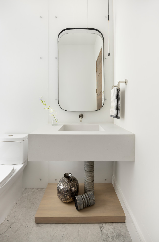 Design ideas for a mid-sized modern powder room in Denver with light wood cabinets, a one-piece toilet, gray tile, grey walls, light hardwood floors, an integrated sink, engineered quartz benchtops, beige floor, white benchtops and a floating vanity.