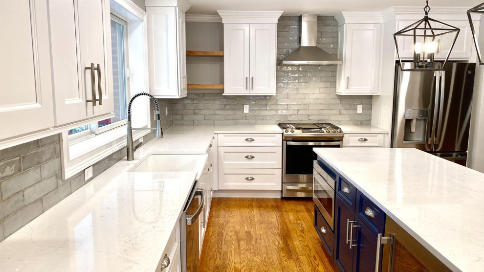 This is an example of a small modern u-shaped eat-in kitchen in New York with a single-bowl sink, recessed-panel cabinets, beige cabinets, granite benchtops, metallic splashback, ceramic splashback, stainless steel appliances, light hardwood floors, a peninsula, multi-coloured floor, white benchtop and vaulted.