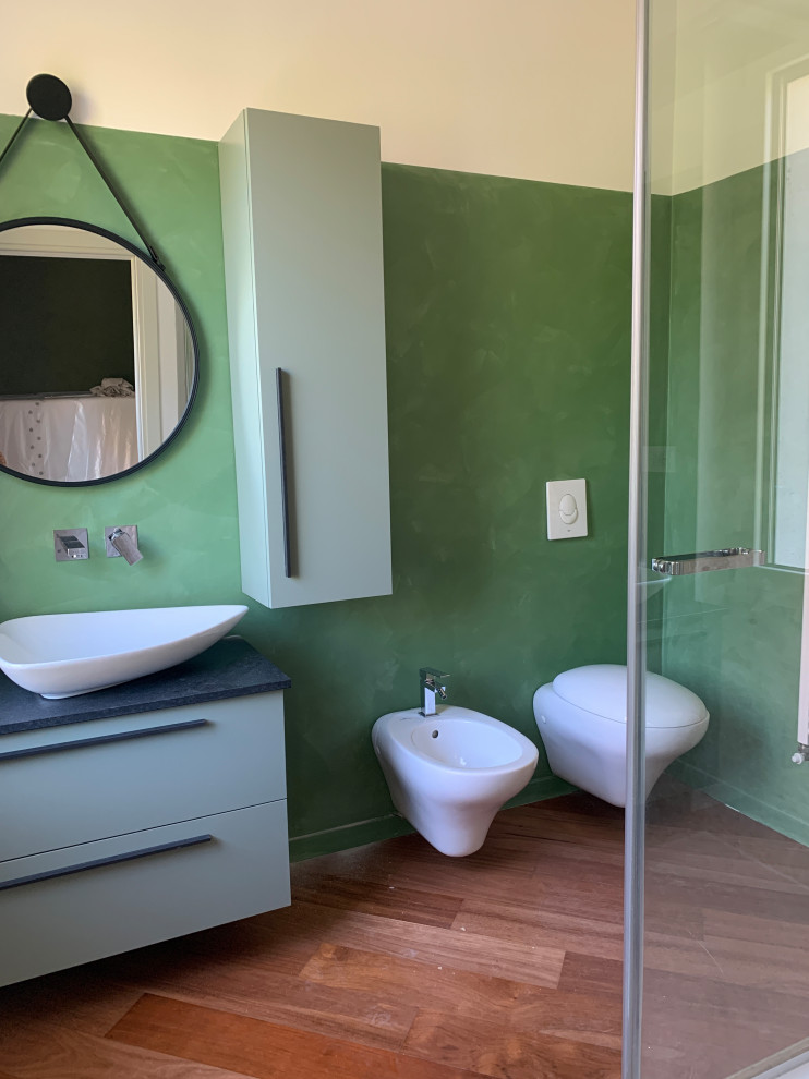 Пример оригинального дизайна: маленькая ванная комната в современном стиле с фасадами островного типа, зелеными фасадами, зеленой плиткой, зелеными стенами, светлым паркетным полом, душевой кабиной, настольной раковиной, столешницей из гранита, душем с распашными дверями, черной столешницей, тумбой под одну раковину и подвесной тумбой для на участке и в саду