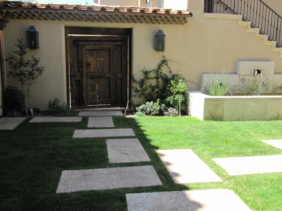 Large mediterranean backyard full sun garden in New York with natural stone pavers for spring.