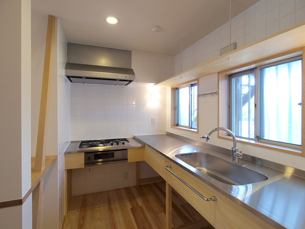 Photo of a scandinavian l-shaped separate kitchen in Other with an integrated sink, open cabinets, stainless steel benchtops and beige floor.