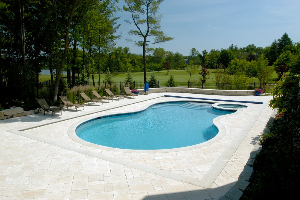 Expansive traditional backyard custom-shaped natural pool in Chicago with a hot tub and natural stone pavers.