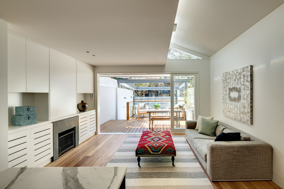 Inspiration for a contemporary formal open concept living room in Sydney with white walls, medium hardwood floors, a standard fireplace, a stone fireplace surround and a concealed tv.