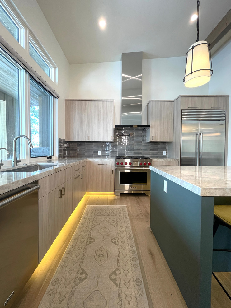 Inspiration for a mid-sized modern l-shaped light wood floor and brown floor eat-in kitchen remodel with an undermount sink, flat-panel cabinets, brown cabinets, quartzite countertops, green backsplash, ceramic backsplash, stainless steel appliances, an island and beige countertops