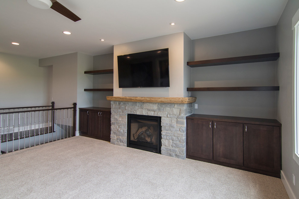 Inspiration for a mid-sized transitional open concept living room in Milwaukee with grey walls, carpet, a standard fireplace, a stone fireplace surround and a wall-mounted tv.