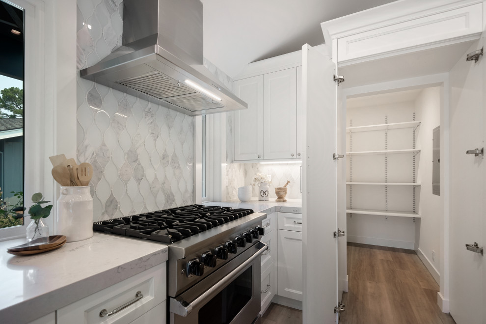 Inspiration for a transitional vaulted ceiling kitchen pantry remodel in San Francisco with recessed-panel cabinets, white cabinets, quartz countertops, white backsplash, glass tile backsplash, stainless steel appliances and white countertops