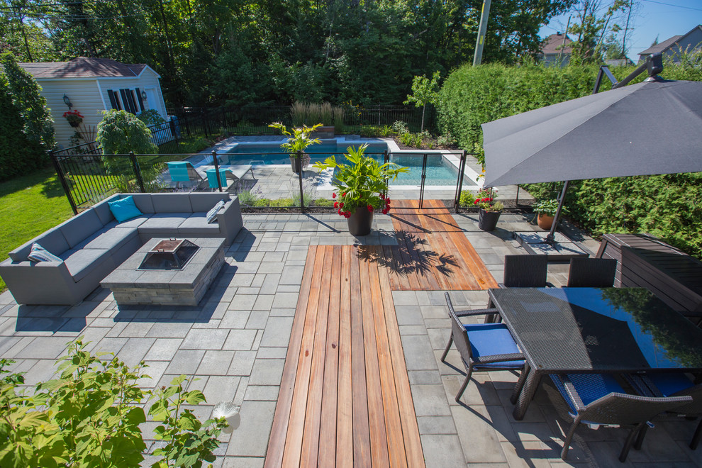 This is an example of a large contemporary backyard patio in Montreal with a fire feature, concrete pavers and no cover.