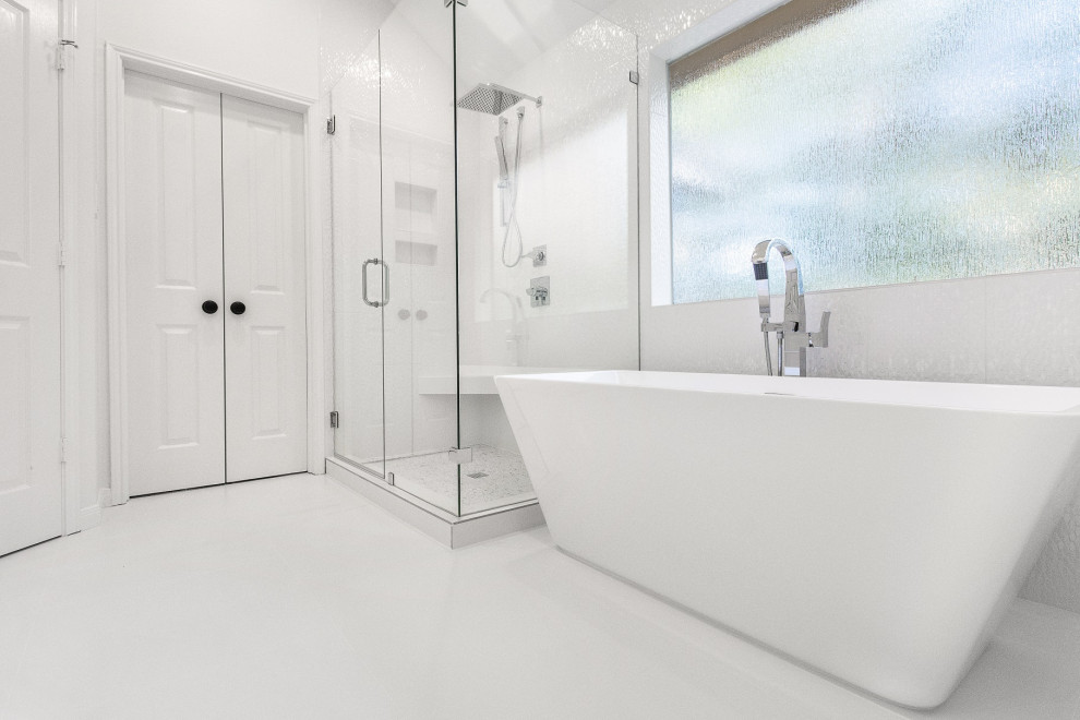Photo of a mid-sized contemporary master bathroom in Houston with raised-panel cabinets, white cabinets, a freestanding tub, a corner shower, a two-piece toilet, white tile, ceramic tile, white walls, ceramic floors, an undermount sink, engineered quartz benchtops, white floor, a hinged shower door and white benchtops.