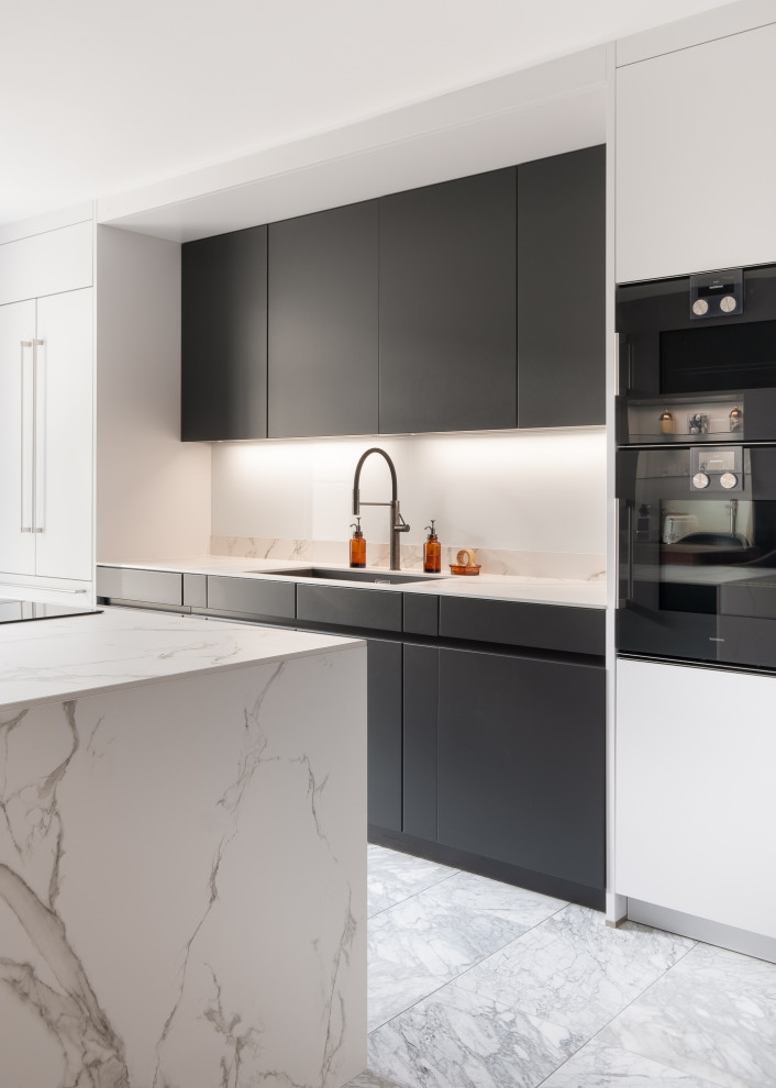 Inspiration for a mid-sized modern galley eat-in kitchen in Gloucestershire with flat-panel cabinets, solid surface benchtops, black appliances, marble floors, with island, white benchtop, an undermount sink, black cabinets and grey floor.