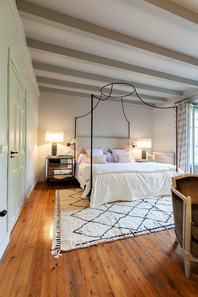 Large transitional master bedroom in Madrid with white walls, medium hardwood floors and no fireplace.