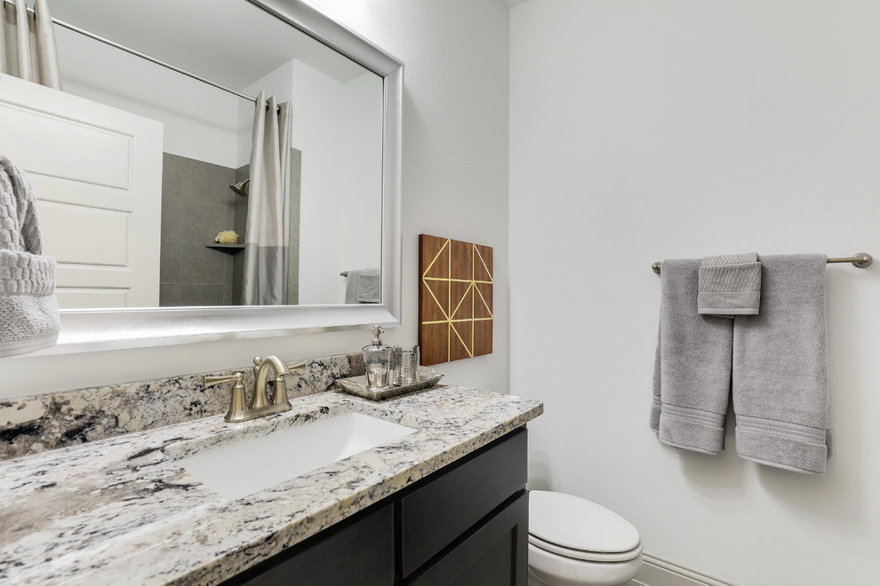 Large traditional kids bathroom in Dallas with raised-panel cabinets, dark wood cabinets, an alcove tub, a shower/bathtub combo, gray tile, ceramic tile, white walls, ceramic floors, an undermount sink, granite benchtops, grey floor, a shower curtain and beige benchtops.