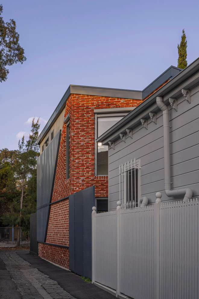 Design ideas for a mid-sized modern two-storey brick red house exterior in Melbourne with a metal roof and a grey roof.
