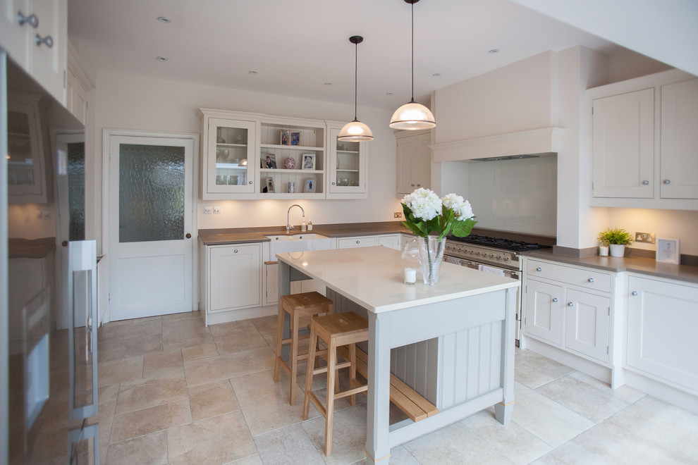 Inspiration for a mid-sized traditional u-shaped kitchen in Surrey with a farmhouse sink, shaker cabinets, white cabinets, stainless steel appliances, with island and beige floor.