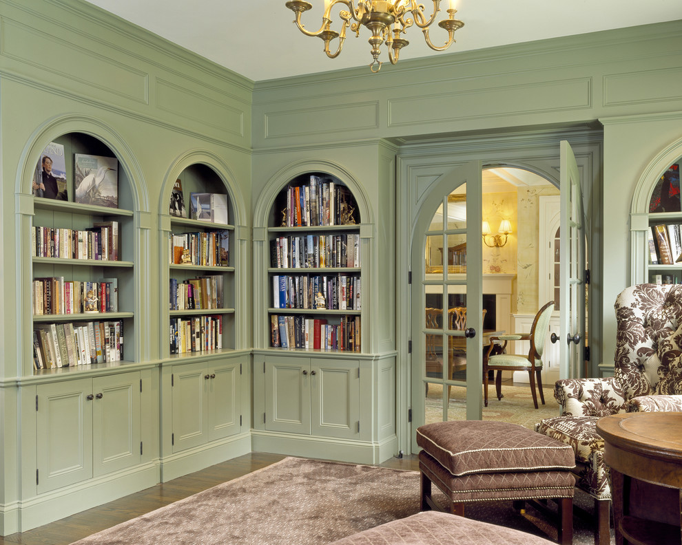 Photo of a large traditional home office in Boston with a library, green walls, dark hardwood floors, a freestanding desk and brown floor.