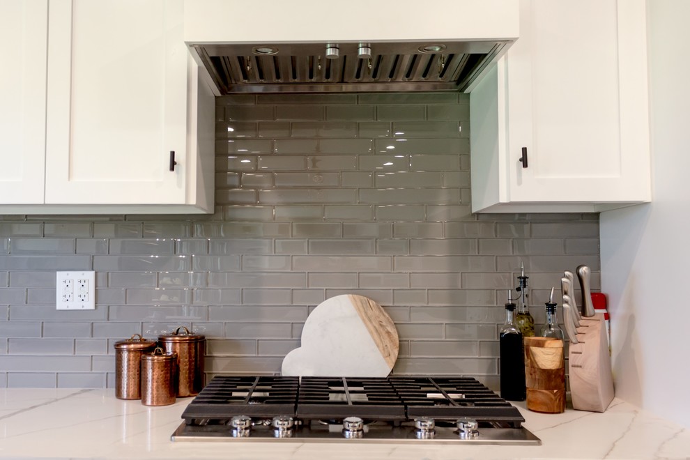 This is an example of a mid-sized contemporary galley open plan kitchen in Los Angeles with a double-bowl sink, open cabinets, white cabinets, marble benchtops, grey splashback, glass tile splashback, stainless steel appliances, dark hardwood floors, with island, brown floor and white benchtop.
