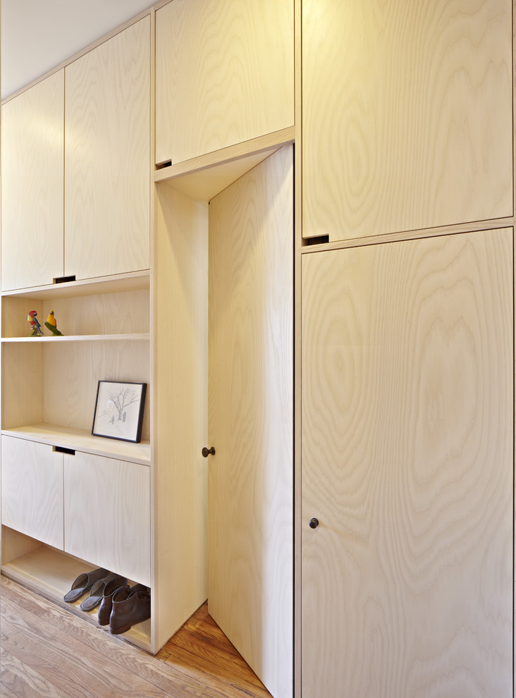 This is an example of a scandinavian gender-neutral built-in wardrobe in New York with flat-panel cabinets, light wood cabinets and medium hardwood floors.
