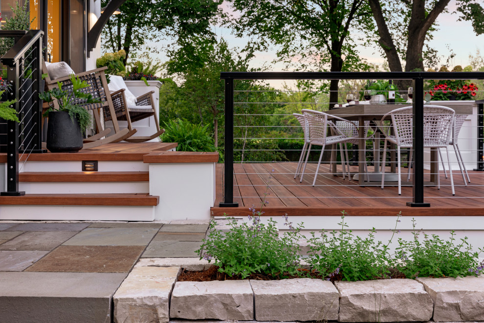 This is an example of a medium sized retro side ground level wire cable railing terrace in Minneapolis with a roof extension.
