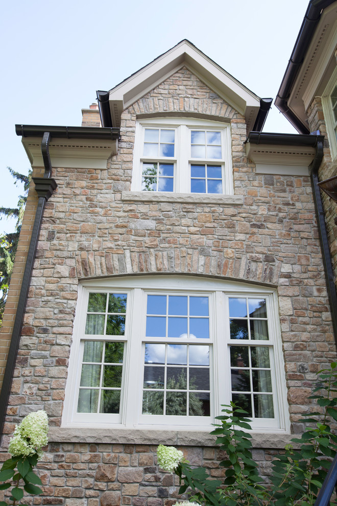 Large traditional two-storey grey exterior in Toronto with stone veneer.