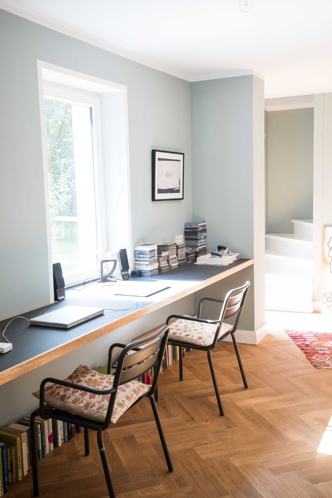 This is an example of a mid-sized transitional study room in Berlin with grey walls, medium hardwood floors, a built-in desk and no fireplace.
