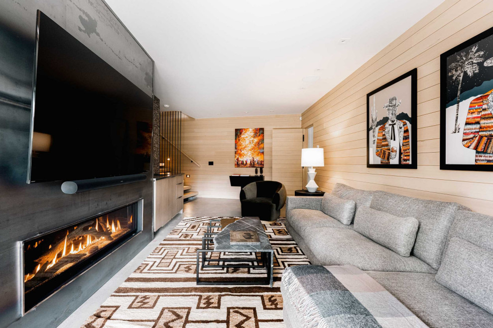Foto di un soggiorno design con pavimento in cemento, camino classico, cornice del camino in metallo, TV a parete e pareti in legno