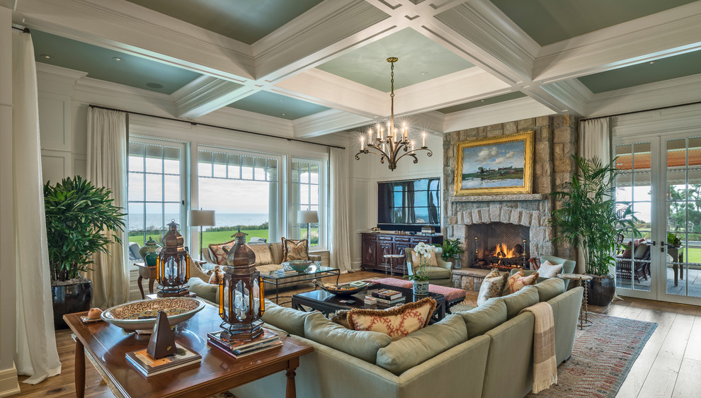 This is an example of an expansive traditional open concept family room in Providence with white walls, medium hardwood floors, a standard fireplace, a stone fireplace surround and a concealed tv.