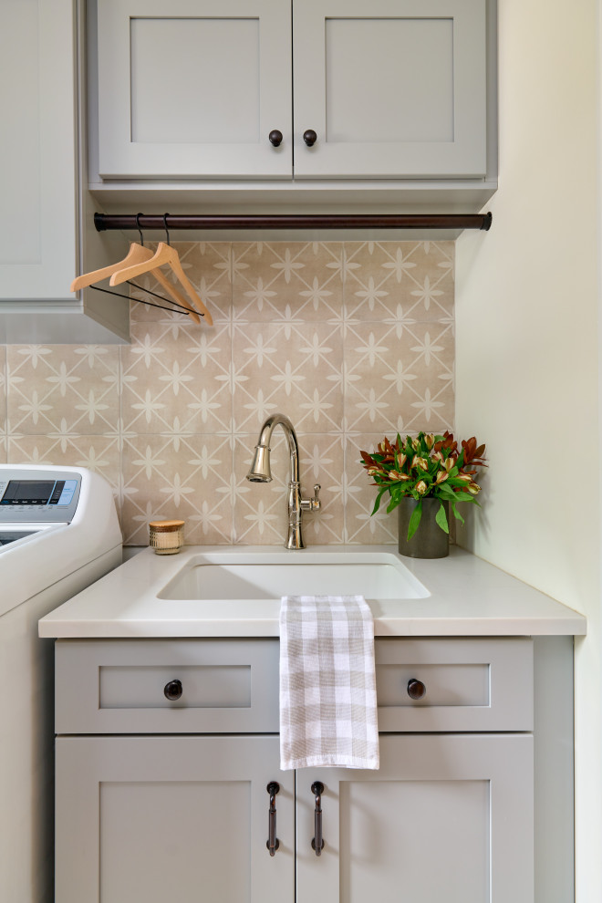 Example of a beach style dedicated laundry room design in New York with shaker cabinets, gray cabinets, quartz countertops, porcelain backsplash, white countertops, an undermount sink and multicolored backsplash