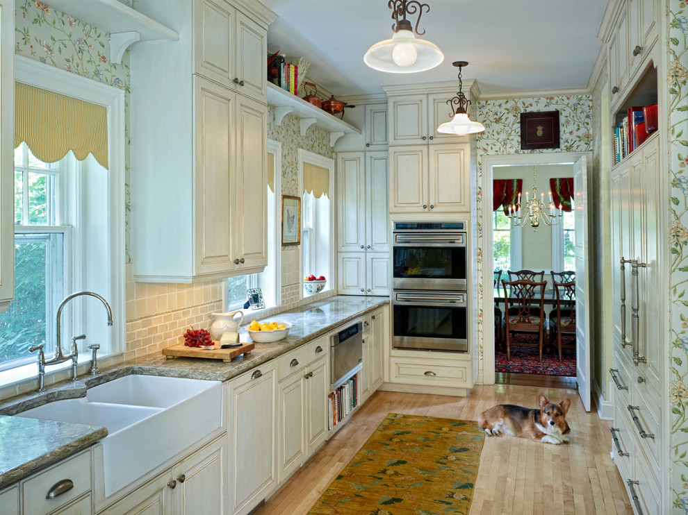 This is an example of a traditional u-shaped separate kitchen in Denver with a farmhouse sink, raised-panel cabinets, beige cabinets, beige splashback and panelled appliances.