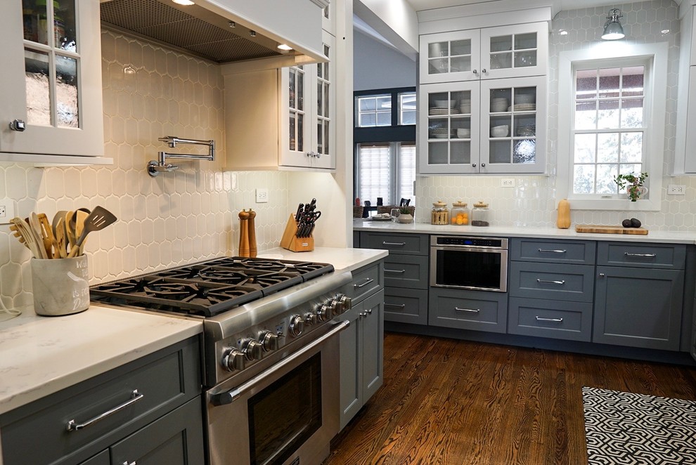 Inspiration for a mid-sized traditional l-shaped eat-in kitchen in Chicago with a farmhouse sink, recessed-panel cabinets, white cabinets, quartz benchtops, white splashback, cement tile splashback, stainless steel appliances, dark hardwood floors, a peninsula, brown floor and white benchtop.
