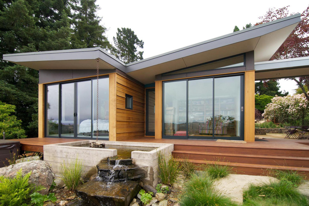 Idee per una terrazza minimalista di medie dimensioni, a piano terra e dietro casa con fontane, un tetto a sbalzo e parapetto in metallo