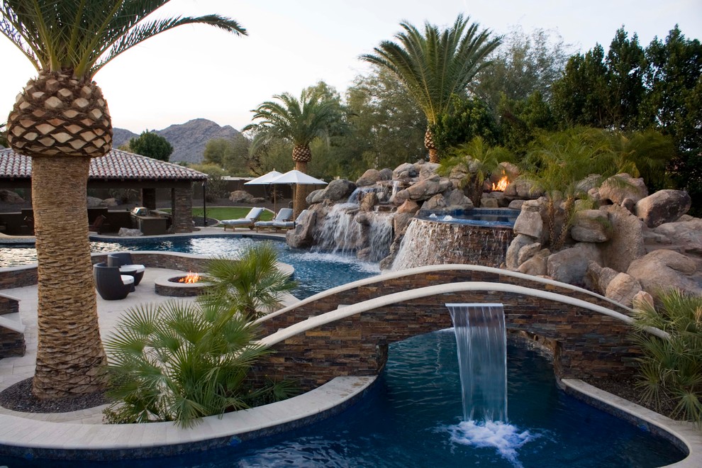 Design ideas for an expansive tropical custom-shaped pool in Phoenix with a water feature.