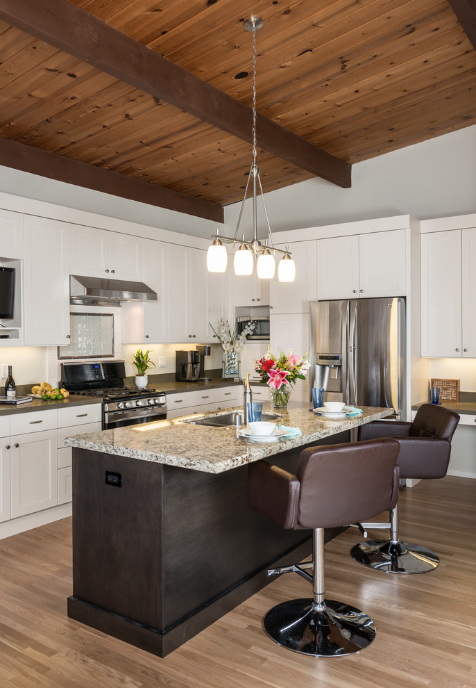 This is an example of a transitional l-shaped kitchen in San Francisco with an undermount sink, shaker cabinets, white cabinets, stainless steel appliances, medium hardwood floors and with island.