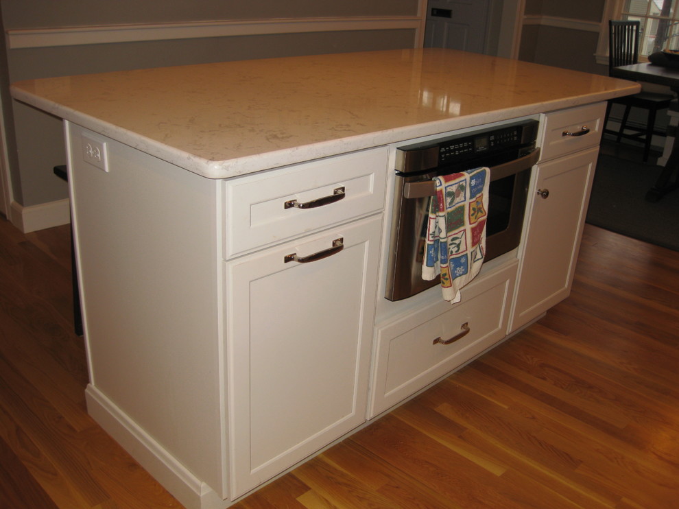 Transitional l-shaped medium tone wood floor eat-in kitchen photo in Boston with an undermount sink, white cabinets, quartz countertops, stainless steel appliances, an island, shaker cabinets, green backsplash, subway tile backsplash and black countertops