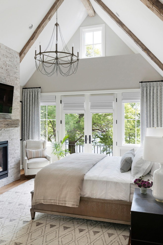 Inspiration for a transitional master medium tone wood floor, brown floor and vaulted ceiling bedroom remodel in Minneapolis with gray walls, a standard fireplace and a stacked stone fireplace