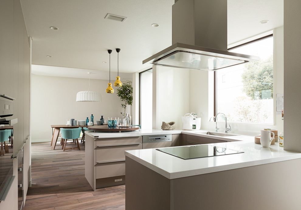 Contemporary u-shaped open plan kitchen in Tokyo with an integrated sink, flat-panel cabinets, grey cabinets, white splashback, medium hardwood floors and brown floor.