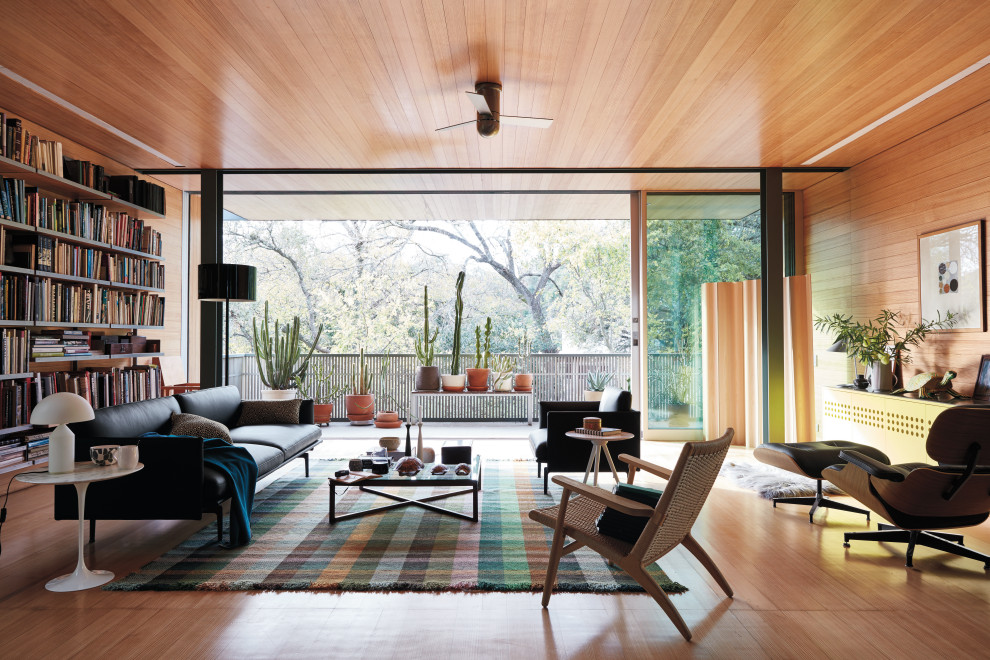 Design ideas for a midcentury open concept living room in Austin with a library, brown walls, medium hardwood floors and brown floor.