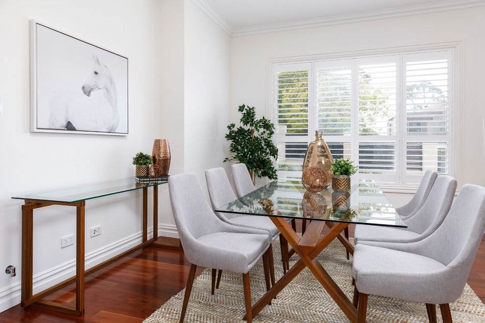 This is an example of a contemporary kitchen/dining combo in Sydney with white walls, medium hardwood floors and brown floor.