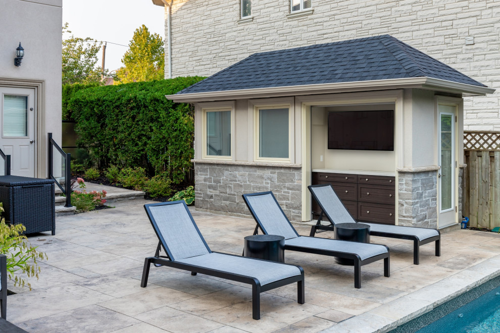 Mid-sized transitional backyard stamped concrete and rectangular pool house photo in Toronto