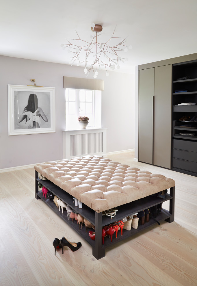 Large contemporary dressing room in London with flat-panel cabinets, light hardwood floors and beige floor.